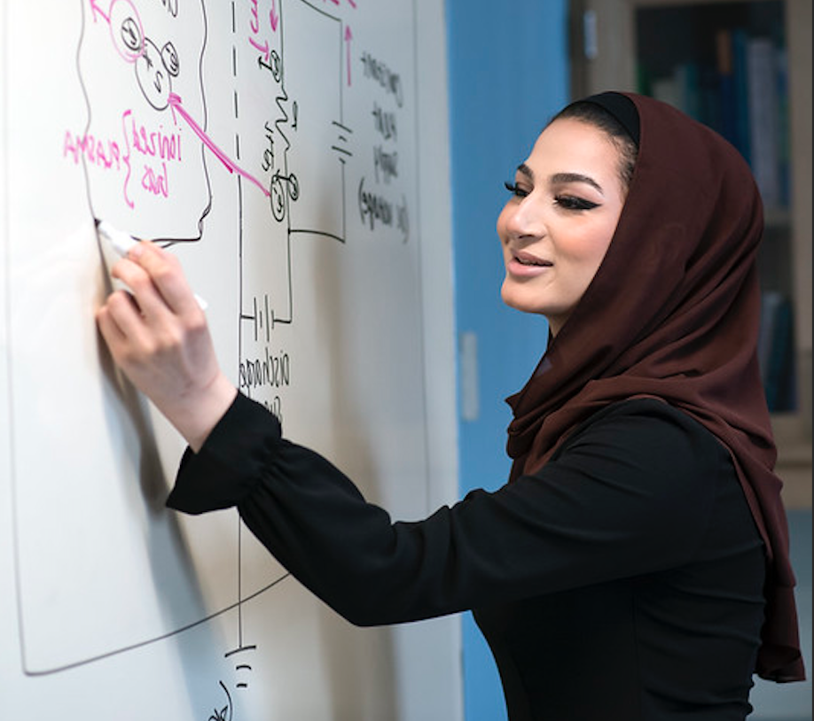 washington scholars student solving a physics problem on a whiteboard